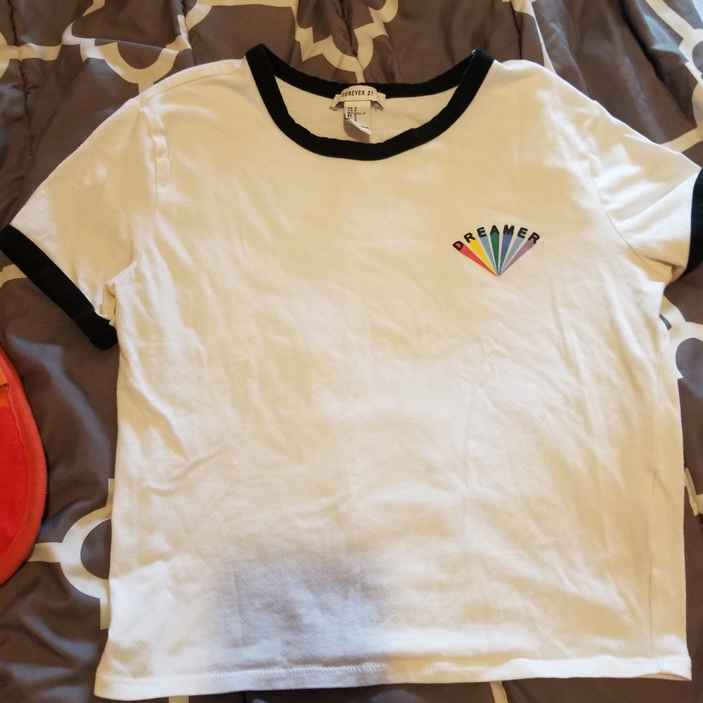 A white top that has a rainbow that says dreamer